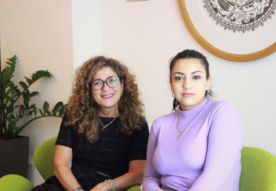 Marina und Kristina sitzen auf grünen Sesseln im Eingangsbereich von Ergon. Oben rechts ist zur Hälfte ein Bild zu sehen, das aus einem runden Scherenschnitt besteht. In der linken Ecke unten steht ein Gummibaum in einem schwarzen Topf. Marina und Kristina sitzen auf grünen Sesseln im Eingangsbereich von Ergon. Oben rechts ist zur Hälfte ein Bild zu sehen, das aus einem runden Scherenschnitt besteht. In der linken Ecke unten steht ein Gummibaum in einem schwarzen Topf.