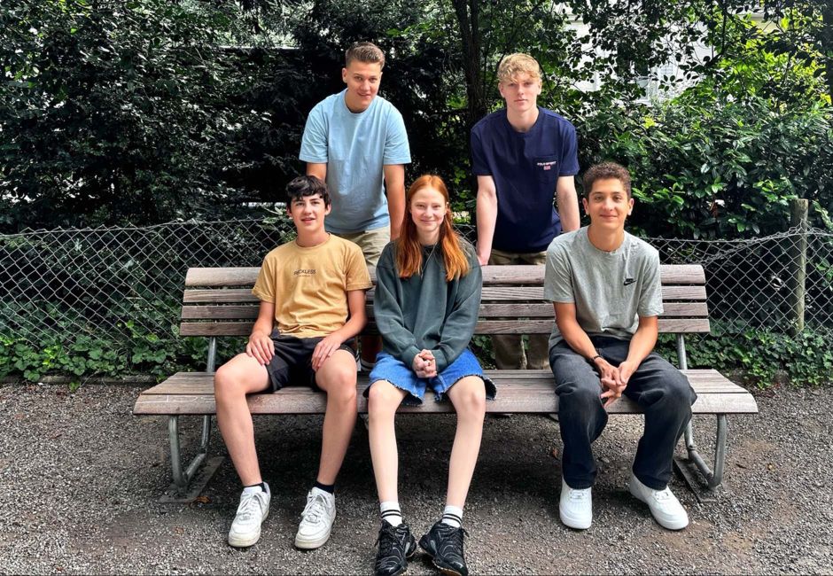 Unsere fünf neuen Lernenden im Park. Drei sitzen auf einer Bank, zwei stehen hinter ihnen. Unsere fünf neuen Lernenden im Park. Drei sitzen auf einer Bank, zwei stehen hinter ihnen.